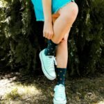 woman in blue sleeveless dress and white shoes sitting on green grass